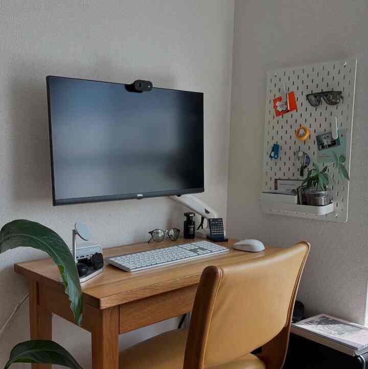 ナチュラルな木目調のコンパクトなホームオフィス、モニターアームと整頓されたデスク、壁掛けペグボードが配置された印象的な空間