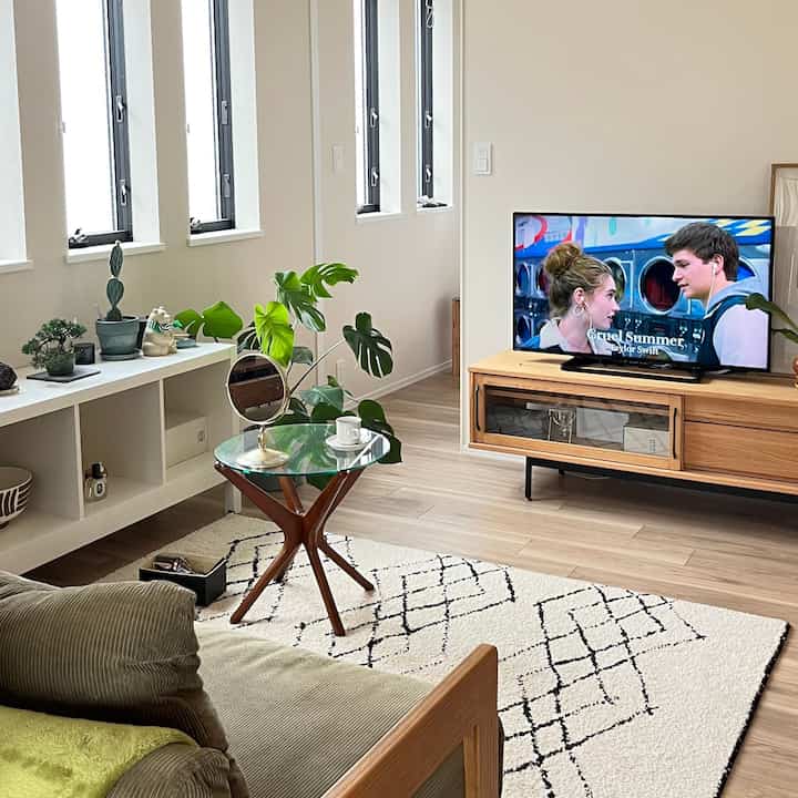 A white and brown toned living room featuring a glass side table and natural wood furniture creating a cozy atmosphere