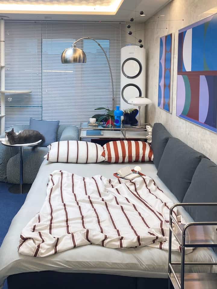 Blue-toned living room featuring a modern sofa bed, floor lamp, and a cat creating a cozy atmosphere