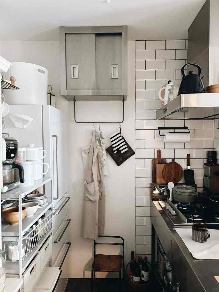 白とステンレスの調和が美しいモダンなキッチンで、収納アイデアと調理器具が整然と配置された雰囲気のある空間