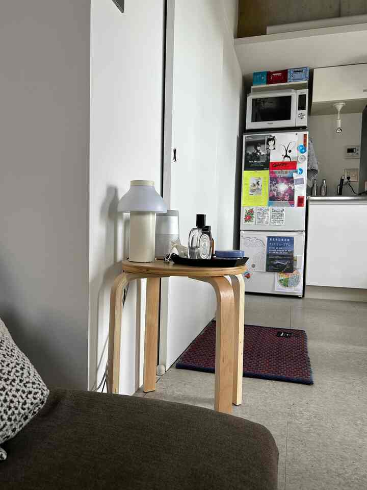 ナチュラルカラーのワンルームキッチンスペース、スツールがサイドテーブルとして配置されたシンプルなインテリア