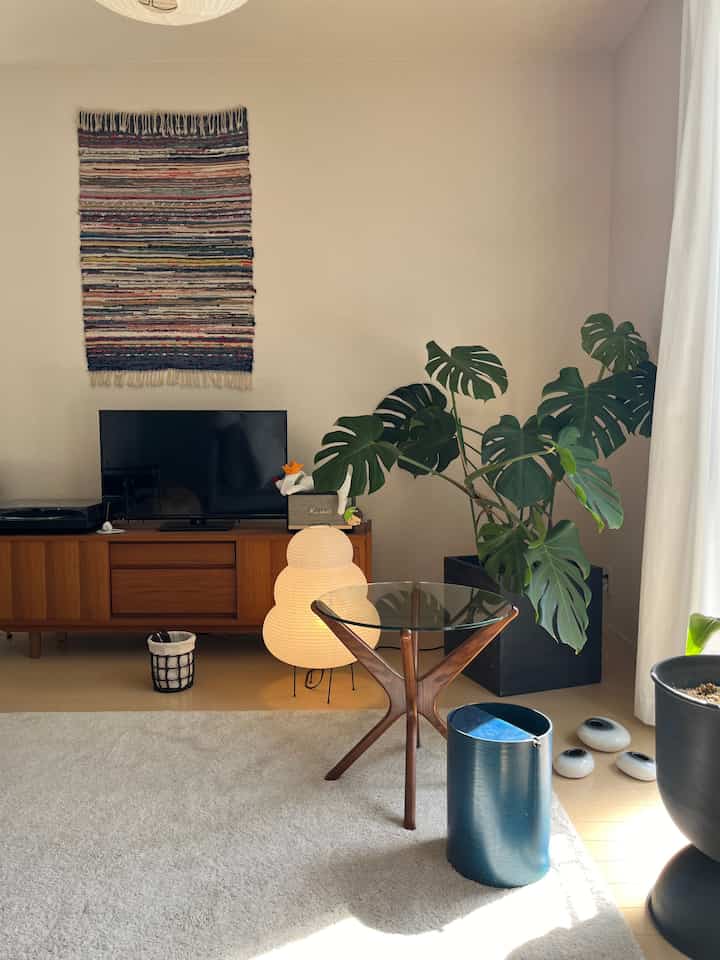 ナチュラルな木目調のリビング、サイドテーブルとフロアランプ、大きな植物が配置された雰囲気のある空間