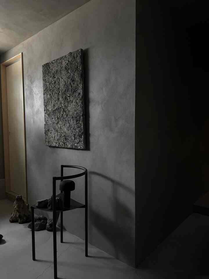 Dark gray toned entrance featuring black art and textured wall décor, with a modern and minimal atmosphere