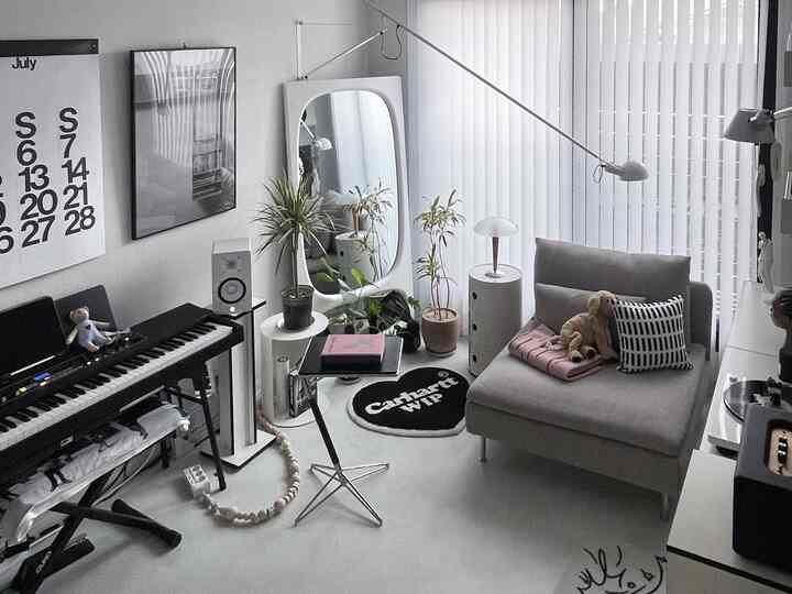 ホワイトとグレーのトーンのリビング、ソファとキーボード、植物が配置されたモダンで清潔感のあるインテリア