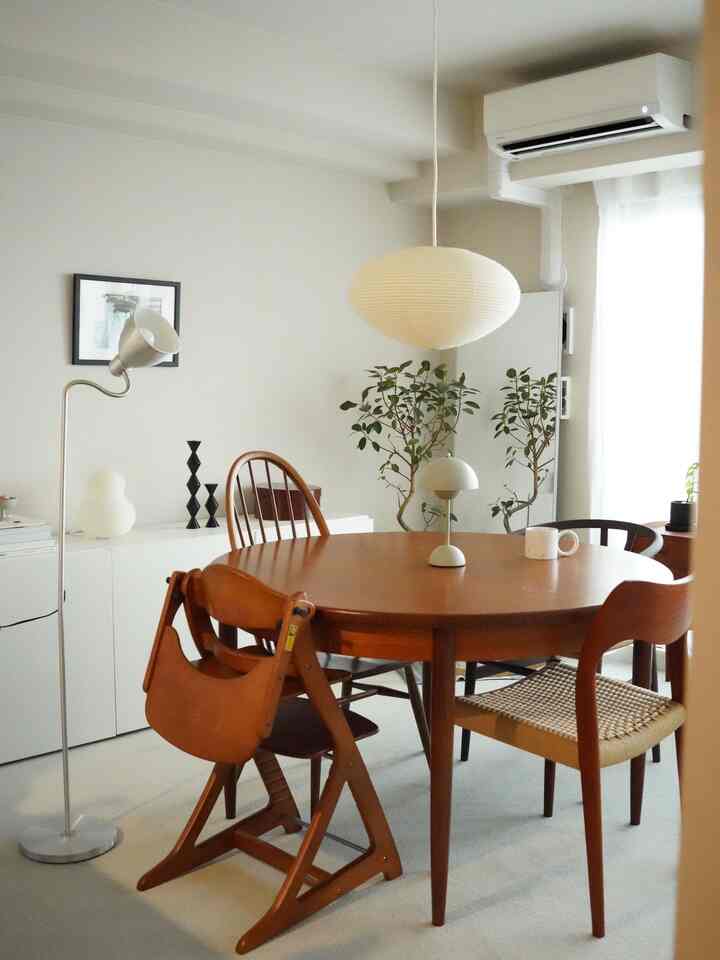 White and wood tone dining room featuring various chairs around a round table, simple and cozy atmosphere