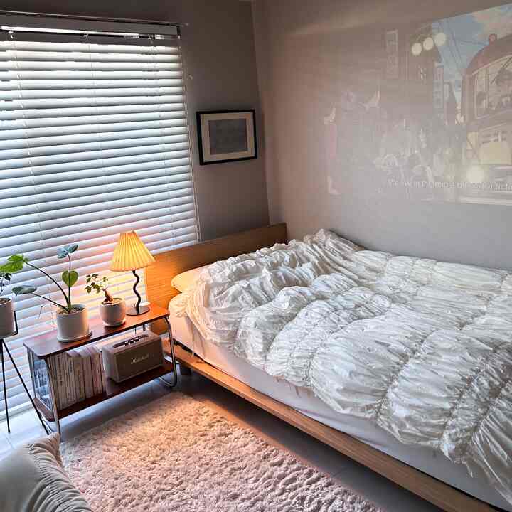 ホワイトとウッドトーンが調和した居心地の良い寝室、ベッドフレームと掛け布団カバーが特徴的なコンパクトな空間