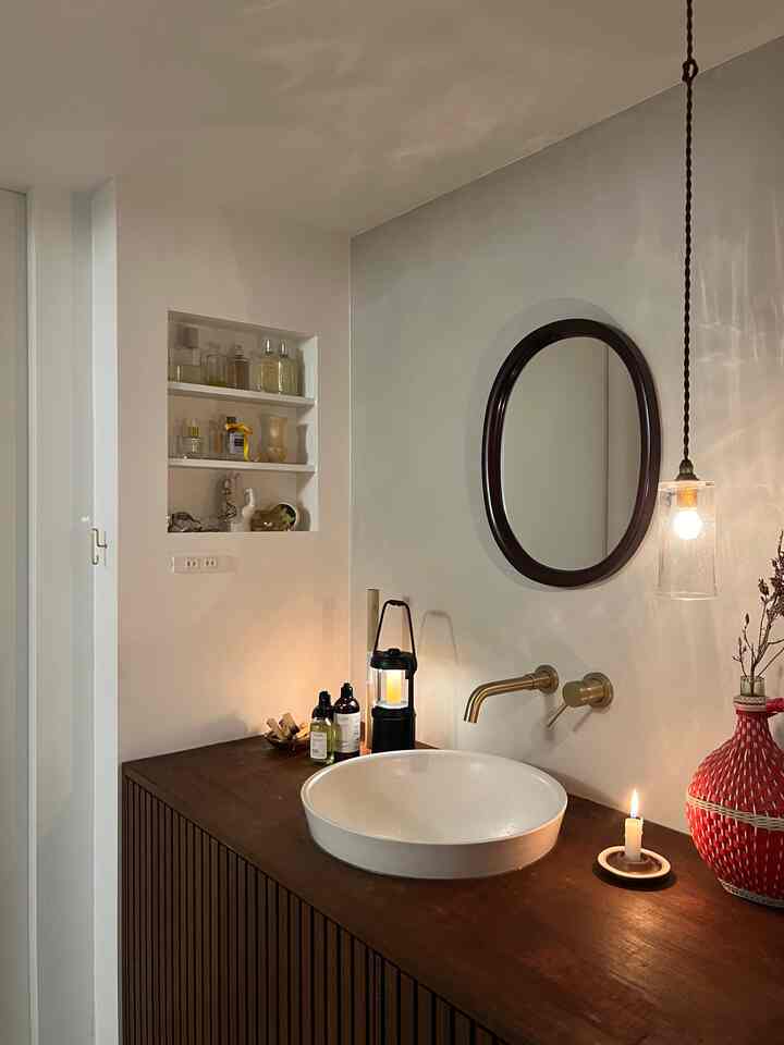 温かみのあるブラウンの木製キャビネットと白い洗面台が配置されたミッドセンチュリーモダンスタイルのホテルライクなバスルーム