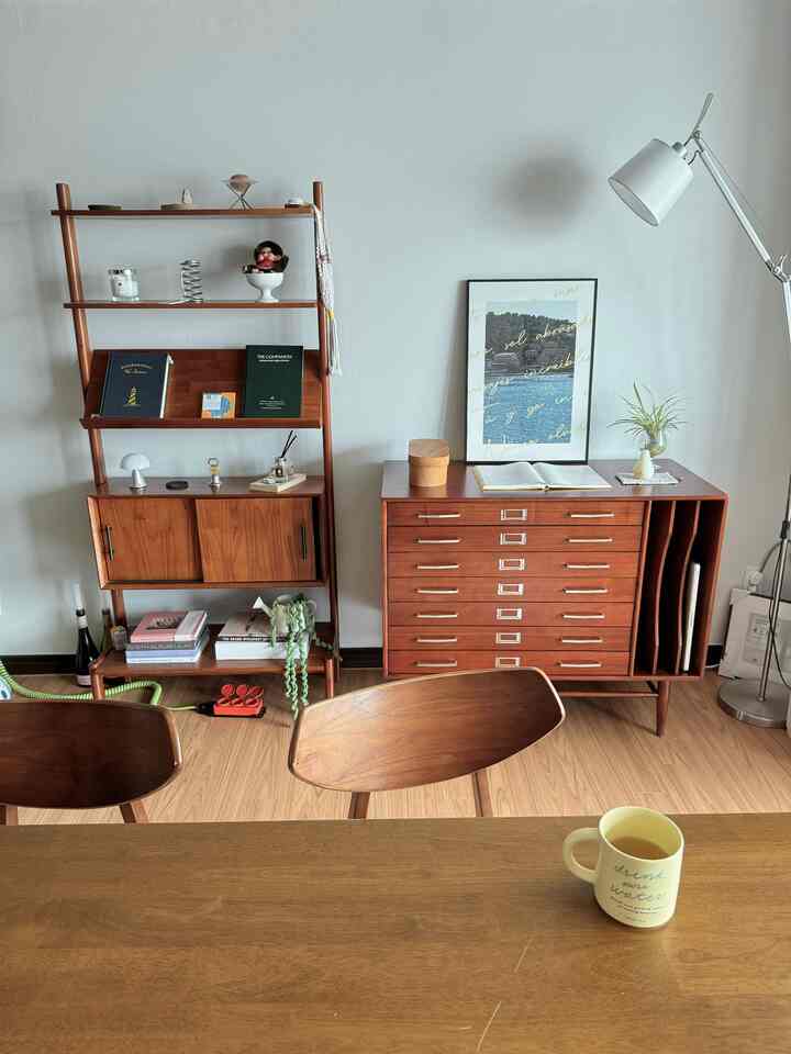 木目調と白を基調としたリビング、木製のキャビネットや本棚、ダイニングチェアが落ち着いた雰囲気のあるインテリア