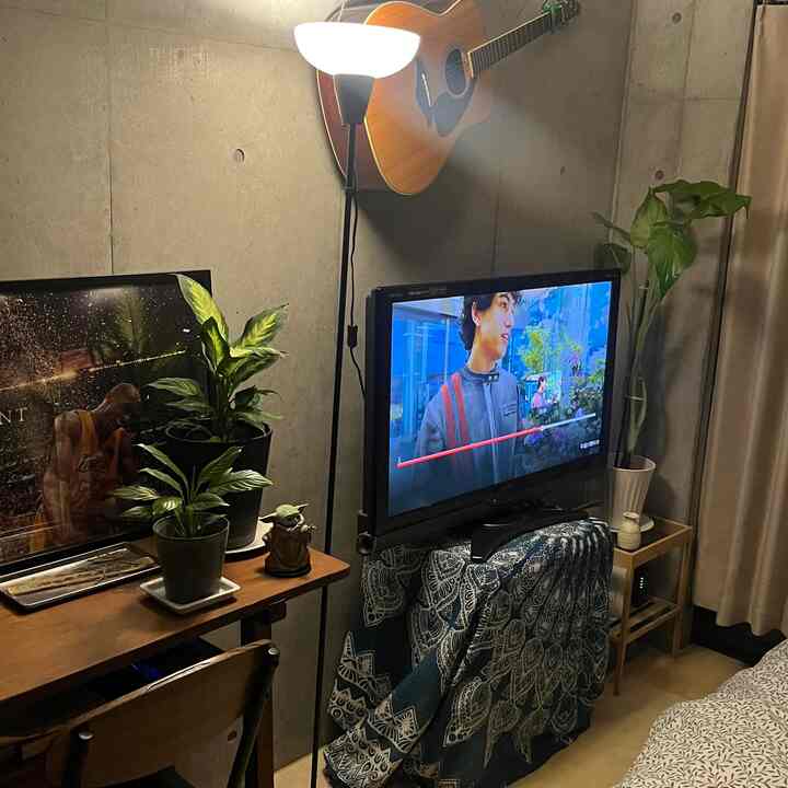 暖かい木目調家具とフロアランプが配置された北欧風の1人暮らしコンパクトな寝室