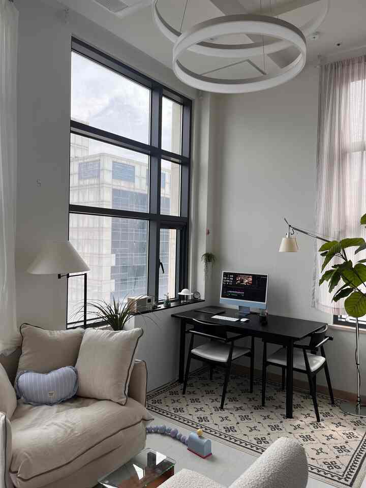 White and black toned studio apartment home office space featuring beige sofa and plants with a modern, simple feel