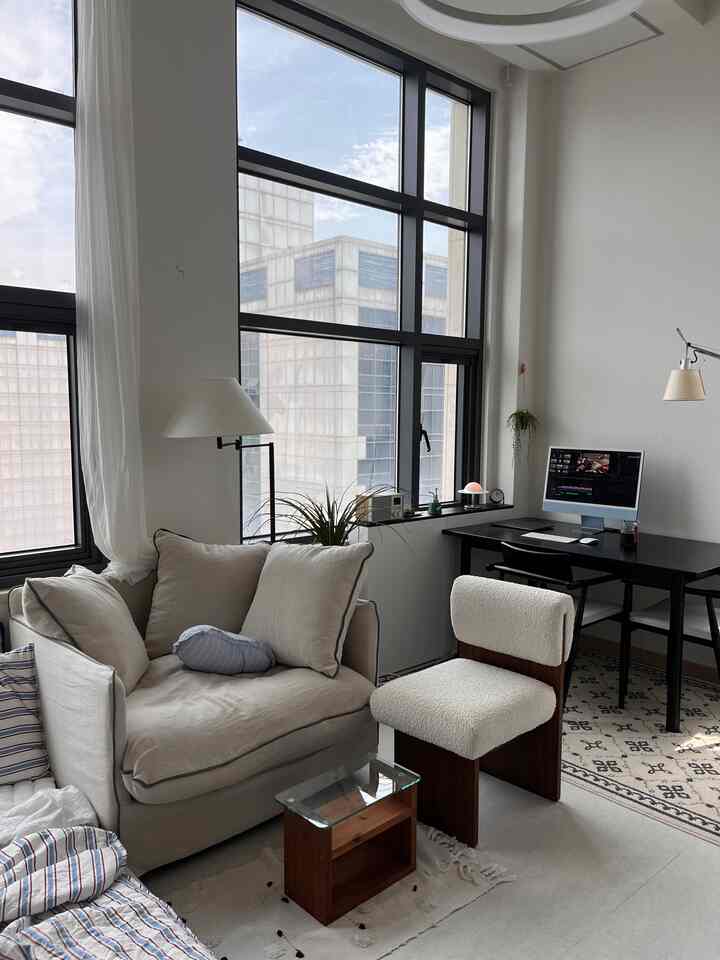 Bright beige and white toned studio apartment featuring a sofa and desk, a clean and modern home office and relaxation space