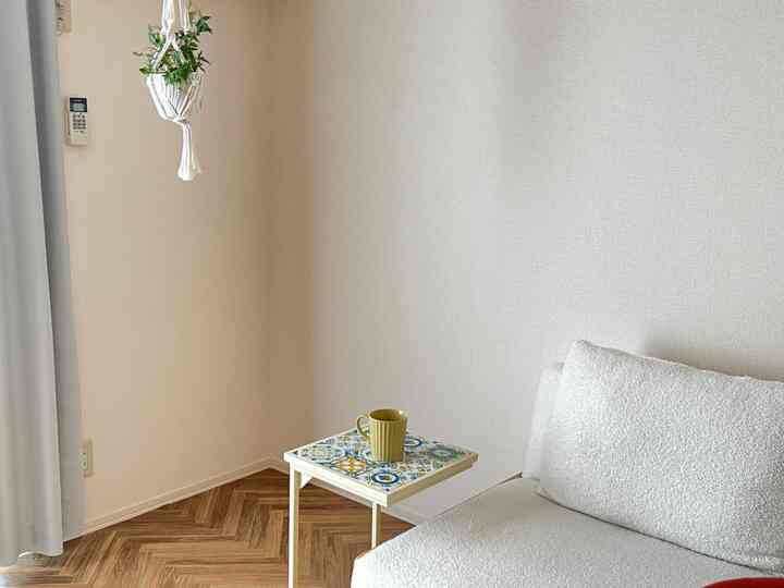 白と木目調が調和したリビング、タイル模様のサイドテーブルとシンプルなソファが配置された雰囲気のあるインテリア