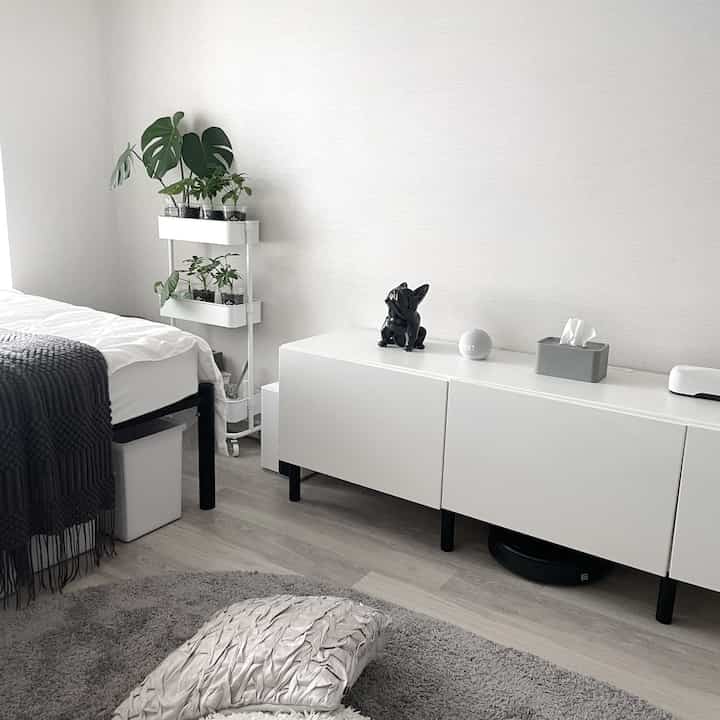 Simple bedroom in white and gray tones featuring plants and modern minimal furniture with a clean atmosphere
