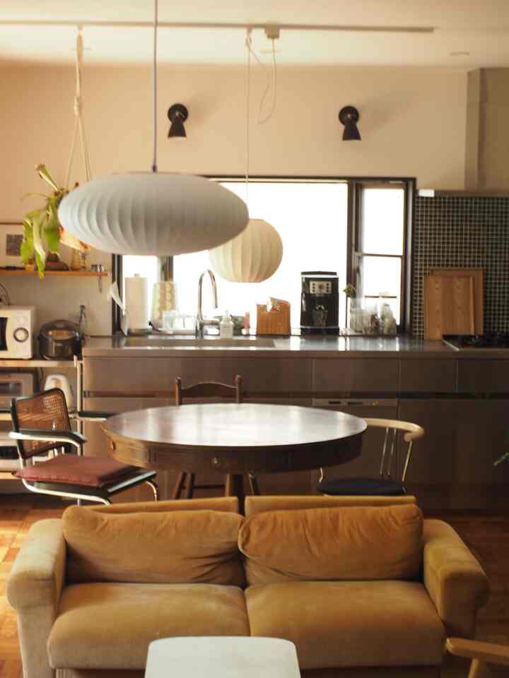 Yellow corduroy sofa and round wooden dining table in a mid-century modern industrial kitchen-living space