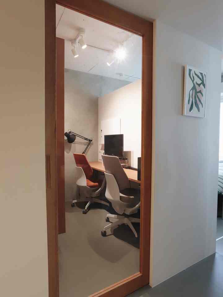 Natural-toned workspace with glass door, two office chairs and desk arranged in a functional room