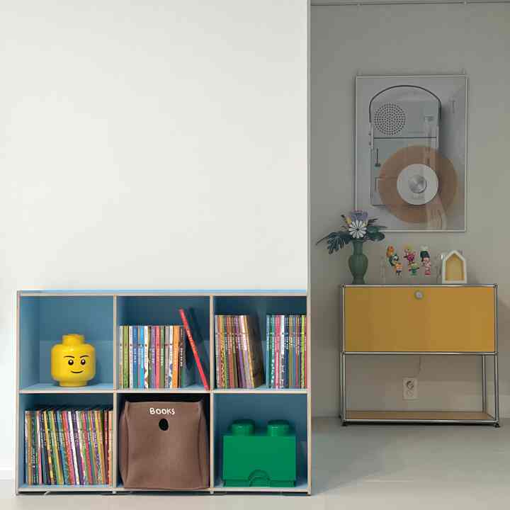 スカイブルーの子供部屋に配置された子供用本棚とイエローの収納キャビネットが調和した印象的なモダンなインテリア