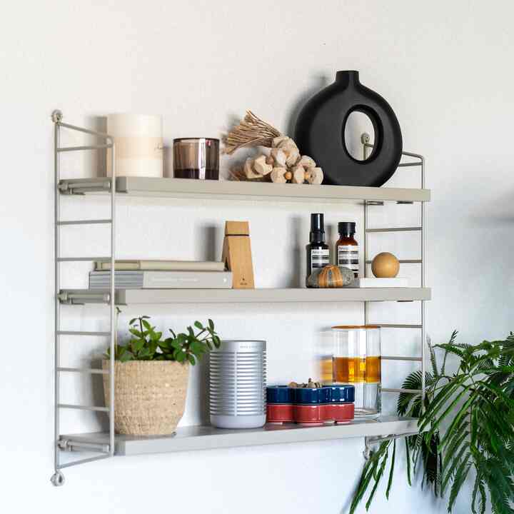 Natural-toned wall shelves with plants, candles, and diffusers arranged in a Japandi style interior