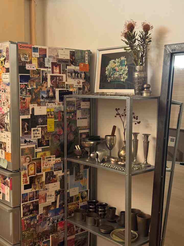 温かみのあるベージュ色調のキッチンスペース、冷蔵庫とメタル棚に多彩な小物が配置された印象的な一人暮らしのインテリア