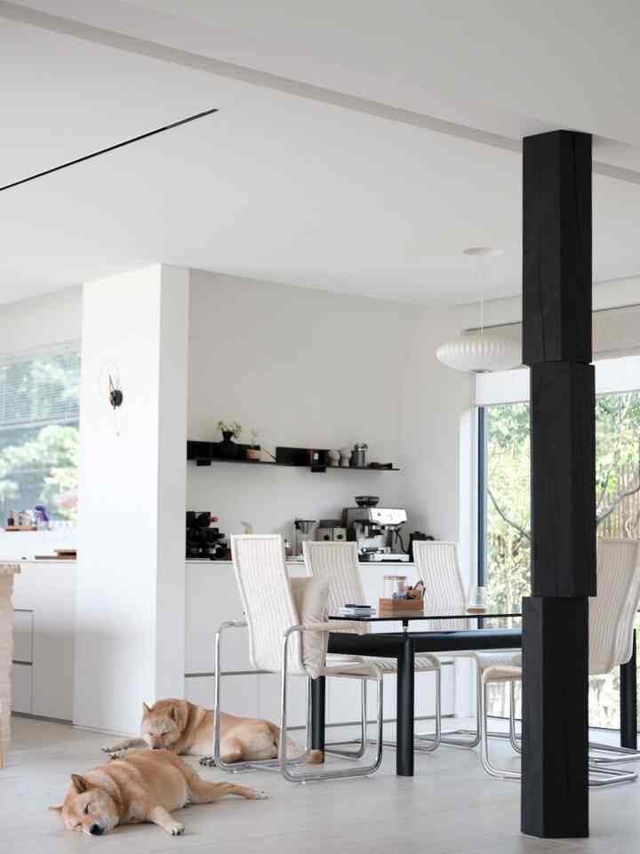 ホワイトとナチュラルトーンのキッチンダイニングスペース、4脚のダイニングチェアと黒いテーブル、バリスタマシンが配置されたモダンで落ち着いた雰囲気のあるインテリア