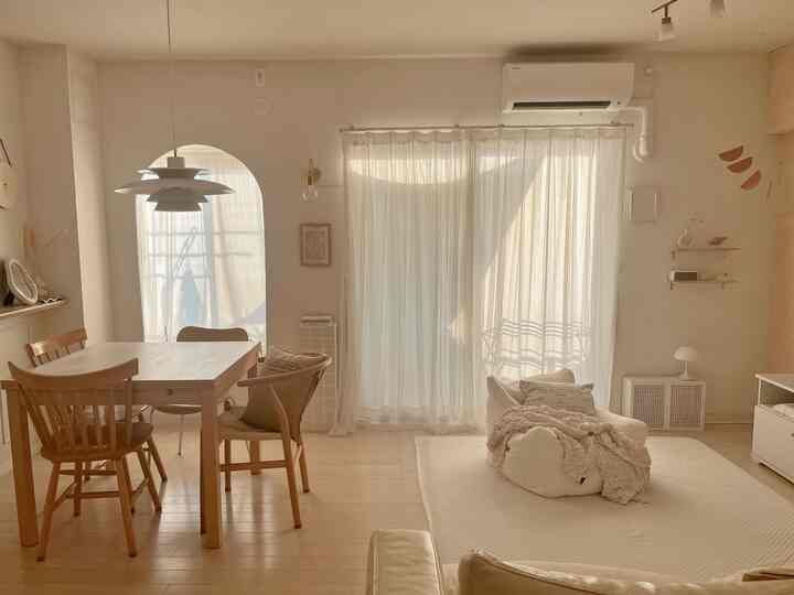 暖かみのあるナチュラルカラーのリビング、木製のダイニングテーブルと一人掛けソファが配置された居心地の良い空間