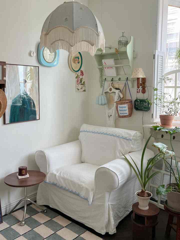 白とミント色調のリビング、白いソファとヴィンテージの小物、観葉植物が配置された雰囲気のある空間