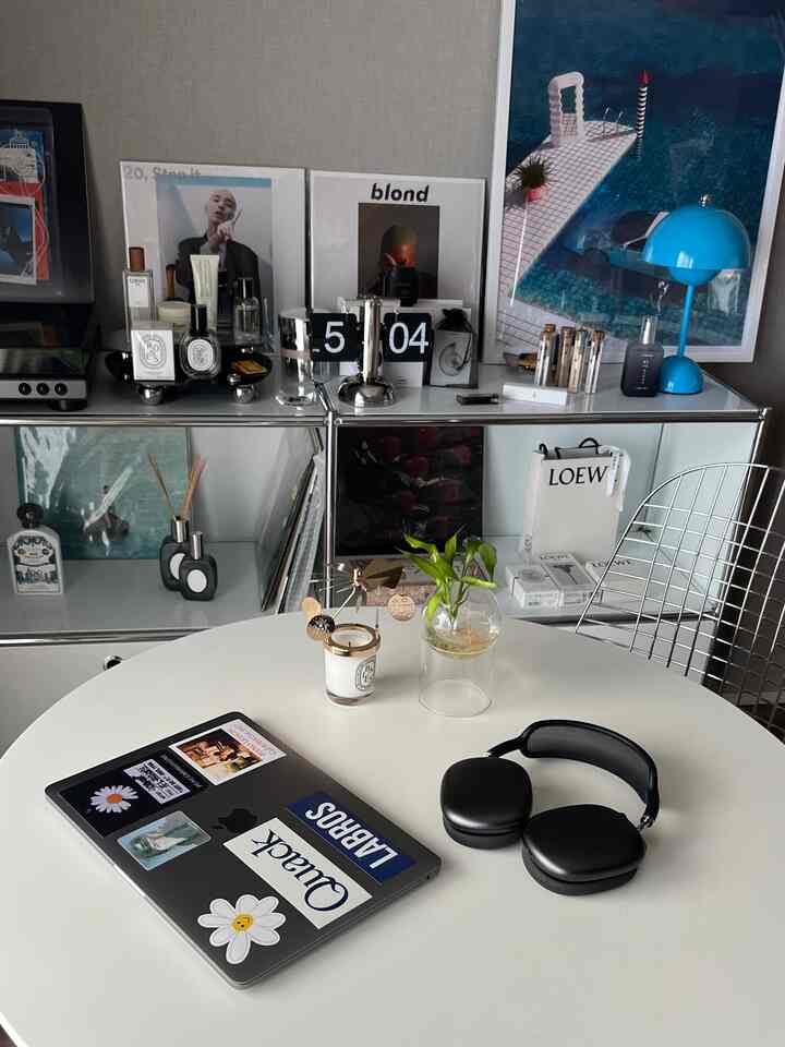 Simple modern dining room in white and gray tones featuring round dining table, laptop, and headphones, evoking a remote work space