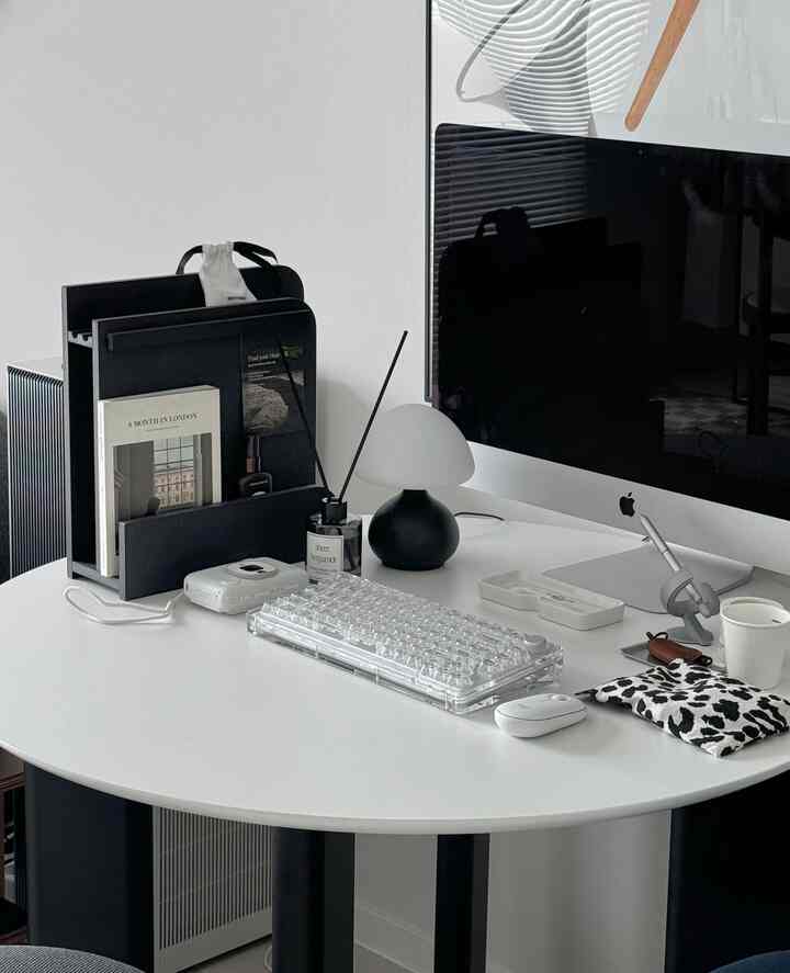 ホワイトとブラックのトーンのモダンなホームオフィス、中央にiMacと透明なキーボードが置かれたすっきりとした作業空間