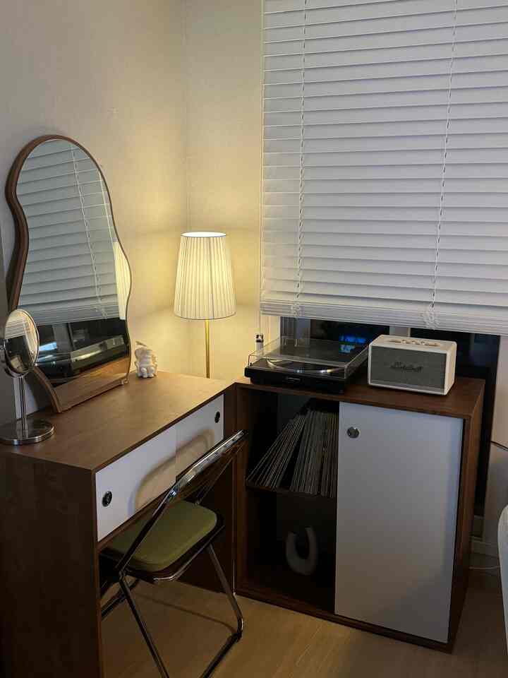 ブラウンとホワイトのトーンのコンパクトなホームオフィス、木製デスクとフロアランプ、オーディオ機器が配置された雰囲気のある空間