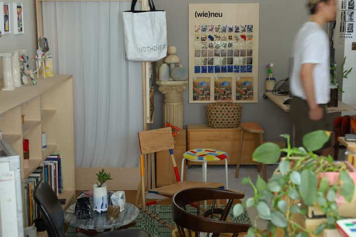 Natural wood tones and vintage decor in a compact studio apartment featuring a desk and stools for a cozy single household space