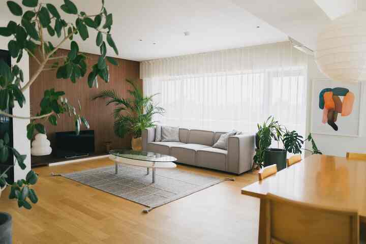 ナチュラルカラーの明るいリビング、グレーのソファと木製ダイニングテーブルが配置された雰囲気のあるインテリア