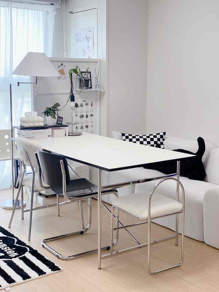 A clean mid-century modern living room with white and wood tones, featuring a minimalist dining table and chairs