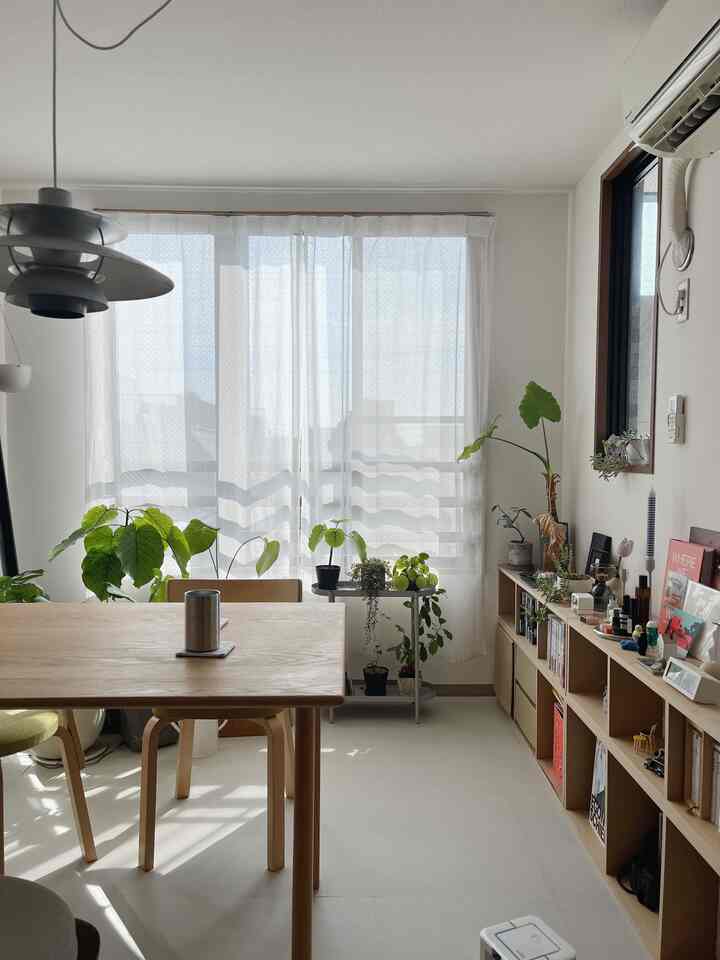 明るくナチュラルな色調の6畳バルコニーの部屋にダイニングテーブルと植物が配置されたシンプルなインテリア