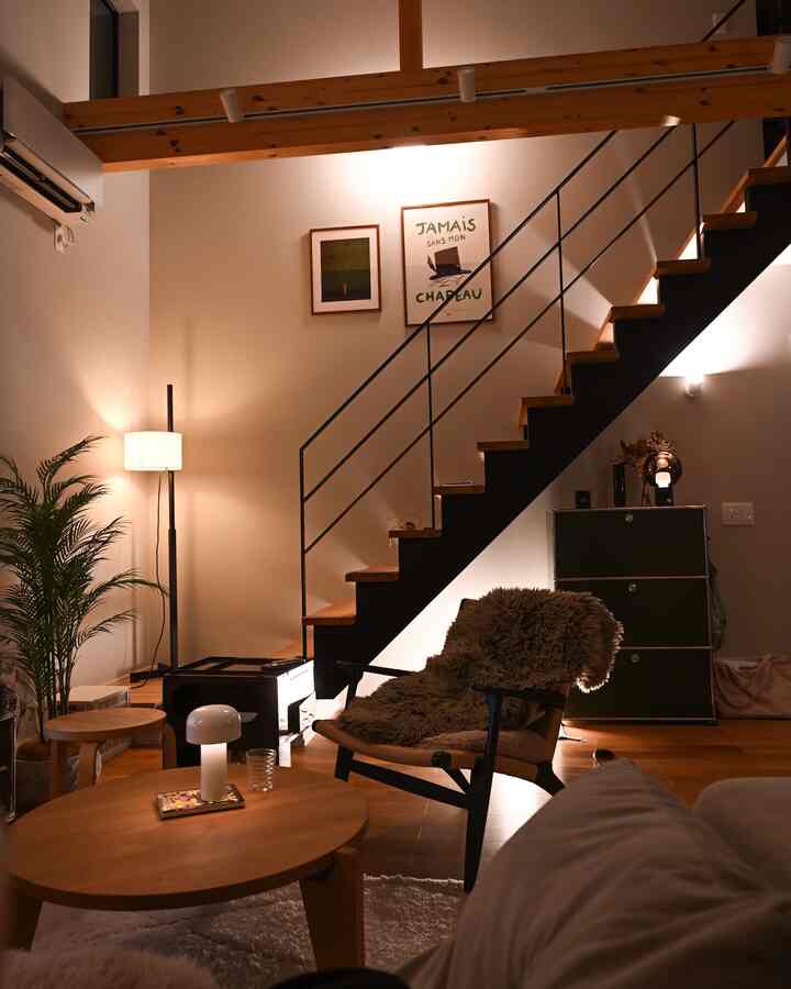 Warm brown and white natural modern living room featuring indirect lighting, wooden furniture, and an interior staircase with a cozy atmosphere