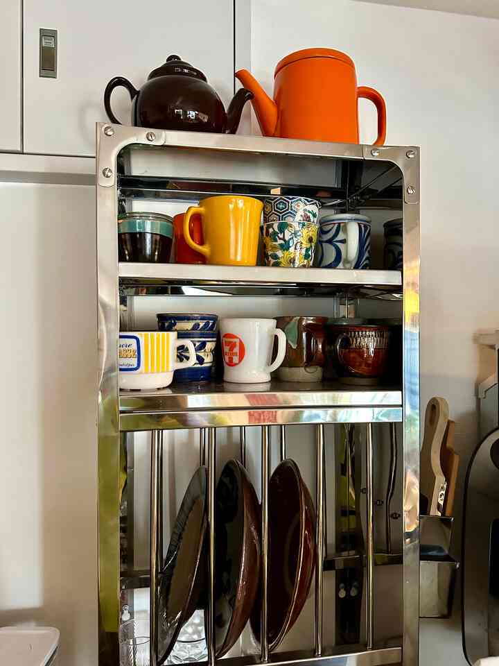 ステンレス製のキッチン皿ラック、色とりどりのマグカップやケトルが並べられた整然としたキッチンのインテリア