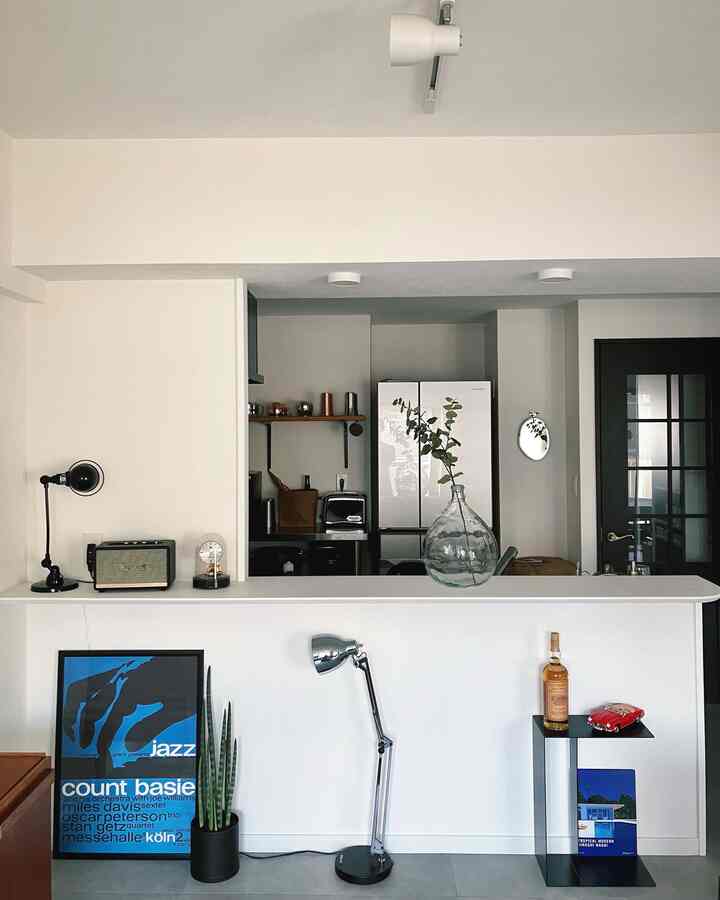 白と黒のトーンが特徴的なモダンなキッチン空間、サイドテーブルとフロアランプが配置されたインテリア