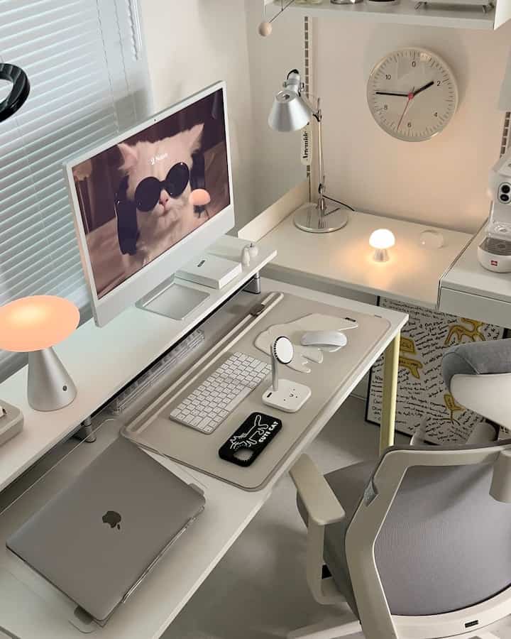 白とグレーのトーンのホームオフィス書斎、猫のイラストのスマホケースと充電スタンドが配置された清潔でモダンなデスクセット