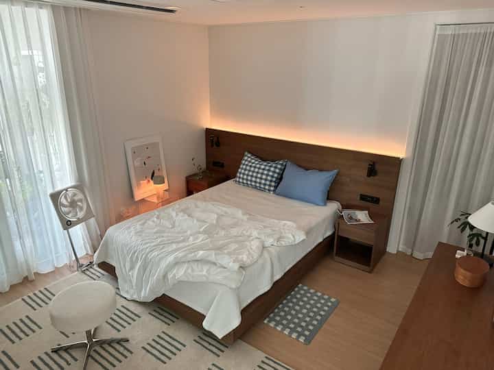 White and brown toned bedroom featuring walnut wood bed and nightstands with a hotel-like atmosphere