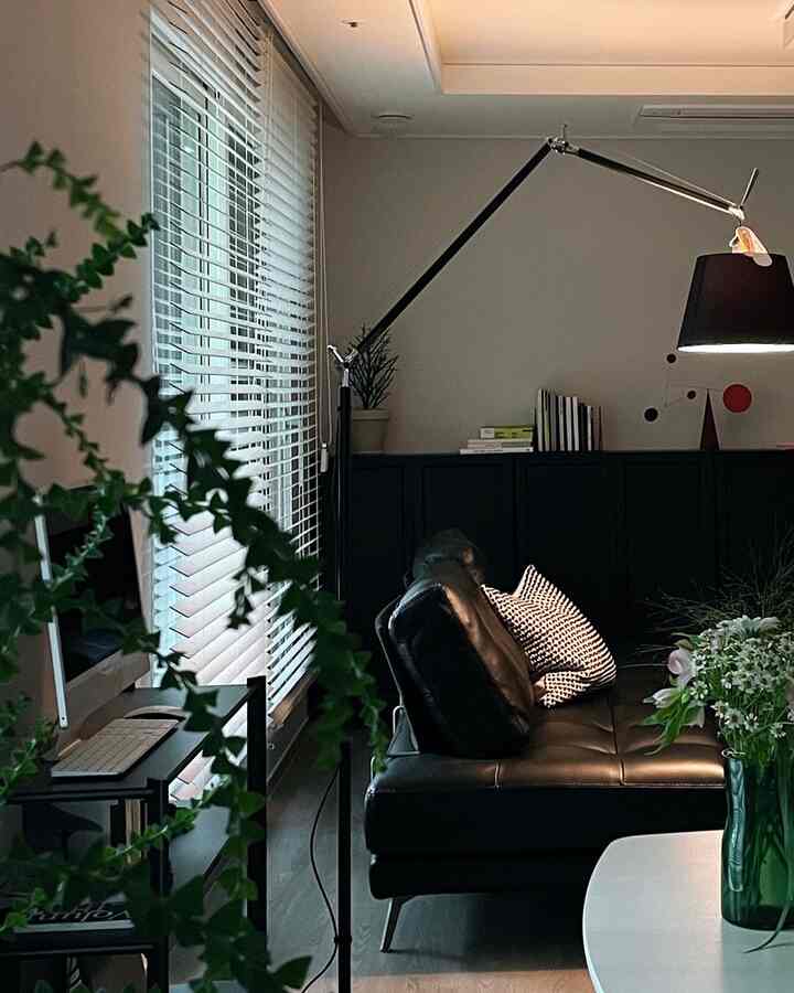 ブラックとホワイトのトーンのリビング、レザーソファとブラインド、フロアランプが配置されたモダンなインテリア