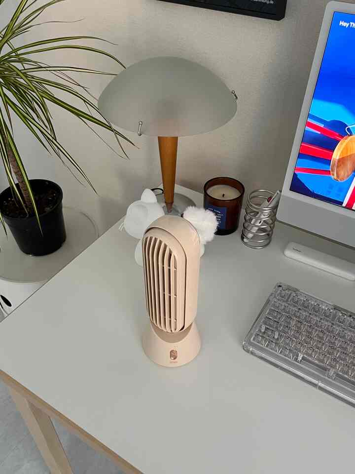 White and beige toned compact home office featuring a mini fan, table lamp, and tidy desk setup