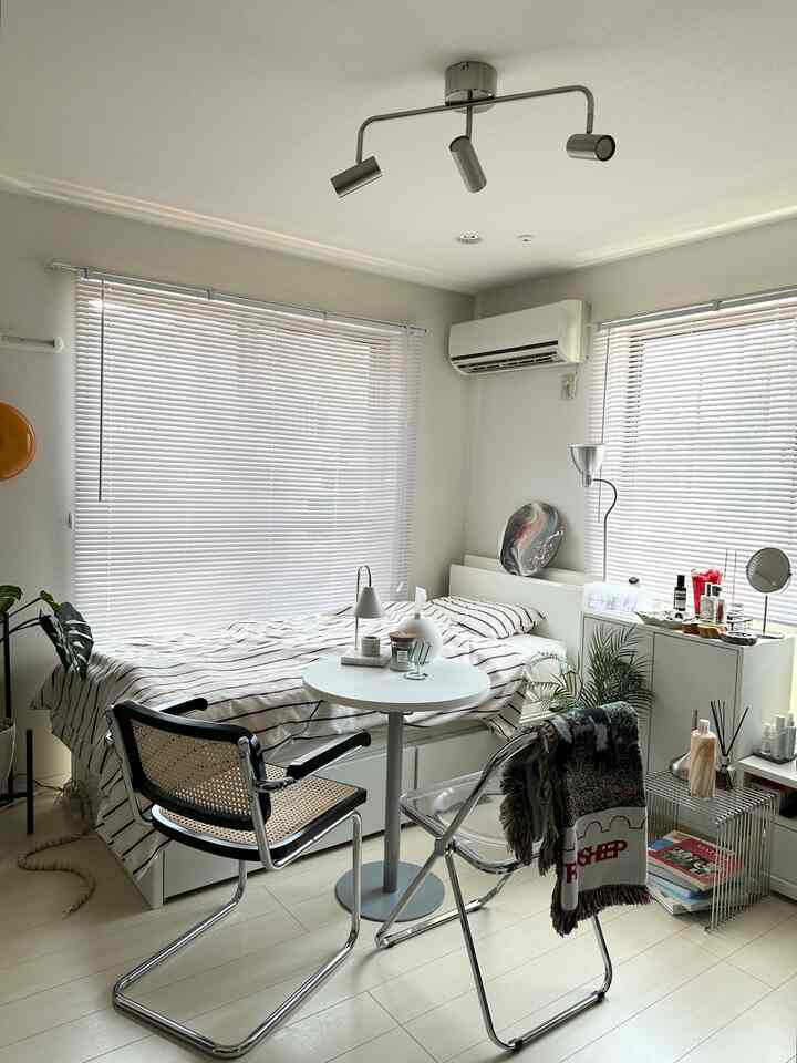 白とブラウンのトーンのワンルーム寝室、すっきりとしたレイアウトとブラインドが印象的な居心地の良い空間