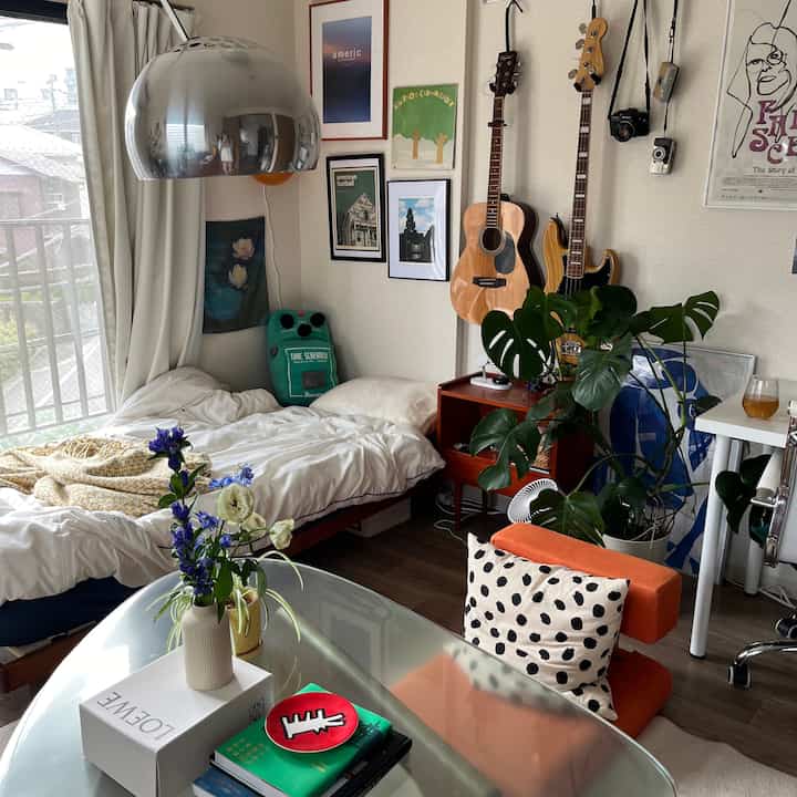 A cozy mid-century modern 8-tatami bedroom with white and green tones, featuring guitars and plants