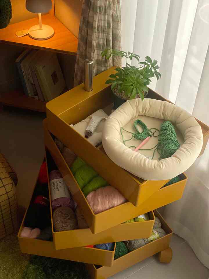 Yellow storage trolley with white curtain and natural light featuring a green plant in cozy corner space