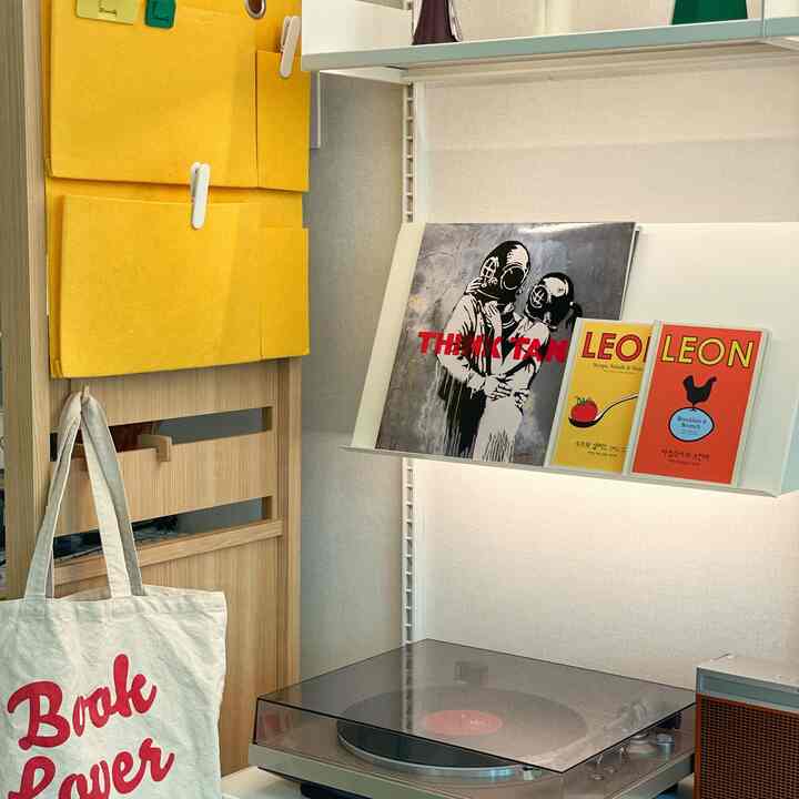 アイボリー調の玄関、木製のデスクと壁棚に本が置かれたミニマルで整った雰囲気のインテリア