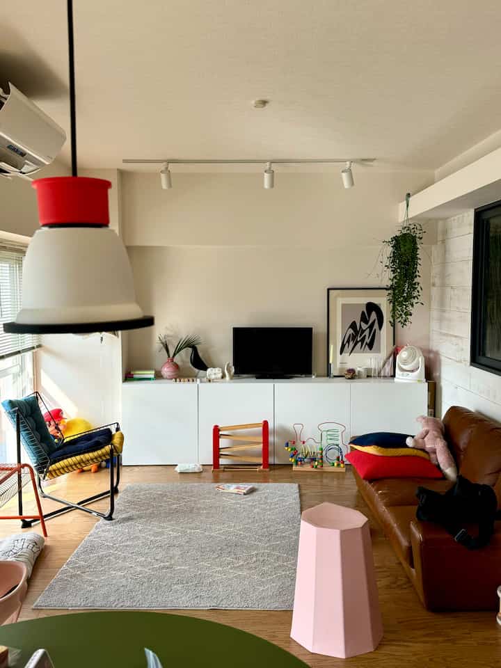 A white and brown toned living room featuring a TV stand, sofa, and children’s toys creating a warm cozy atmosphere