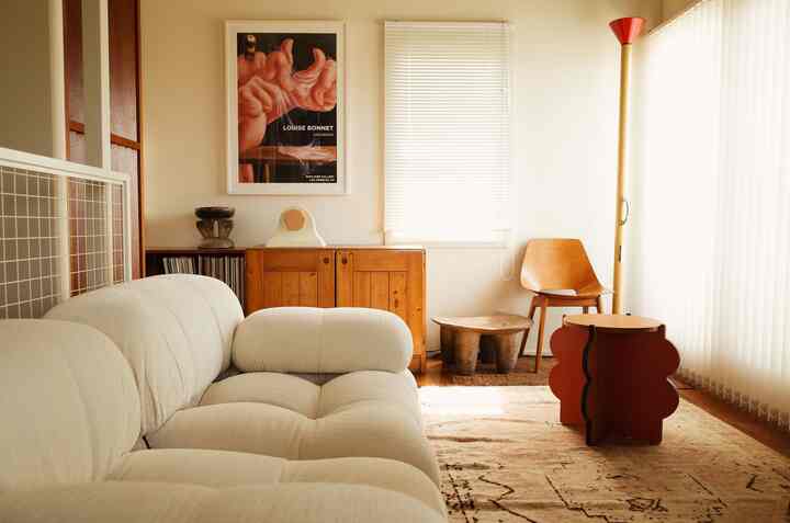 暖かいベージュとナチュラルウッドのトーンが印象的なリビング、クリーム色のソファとヴィンテージキャビネットが配置された雰囲気のあるインテリア