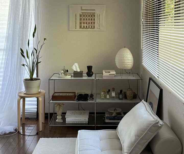 Natural-toned living room featuring a white sofa, wood tone stool, and a plant in a simple, calm space