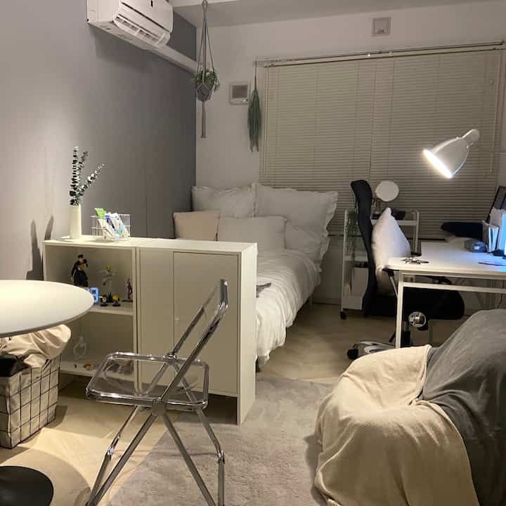 White and gray toned single household bedroom and home office featuring a transparent chair and blinds in a simple, cozy interior