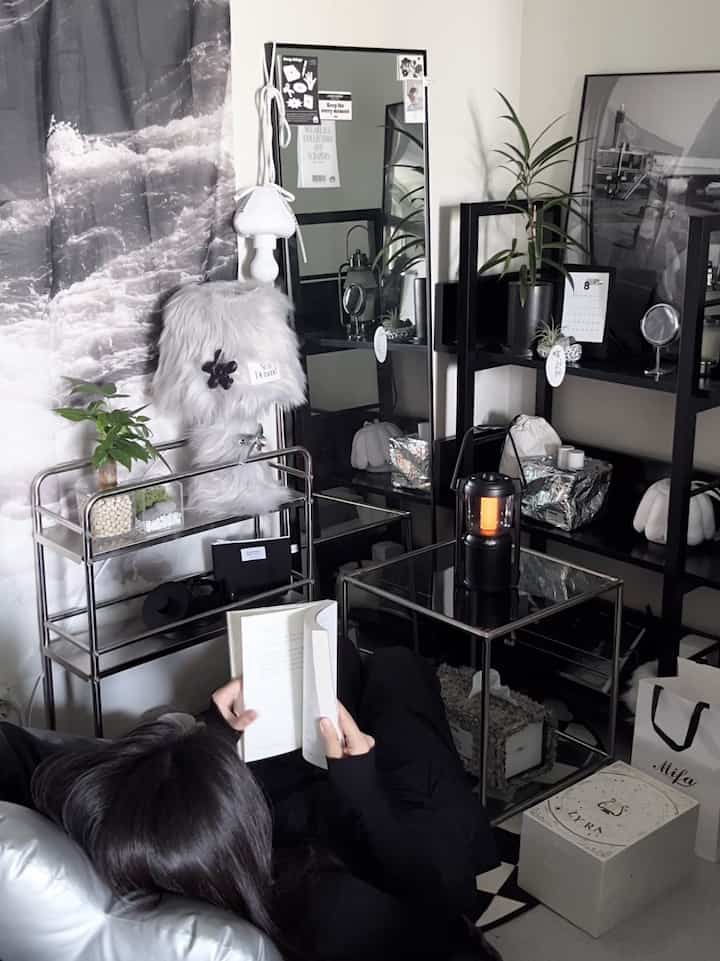 モノトーンのブラックインテリアが印象的なワンルーム、金属家具とラグが配されたモダンで落ち着いた読書空間