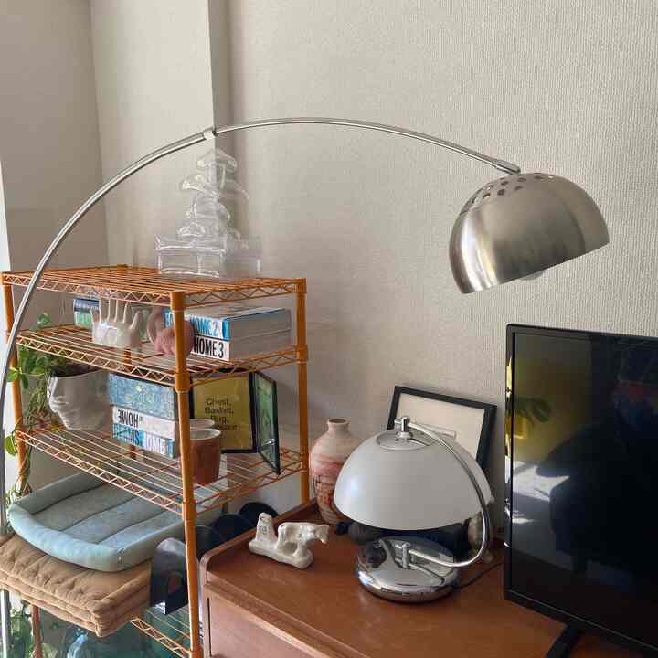 シルバーのフロアランプとヴィンテージのオブジェが配置されたリビング、ナチュラルカラーの家具と調和したモダンなインテリア