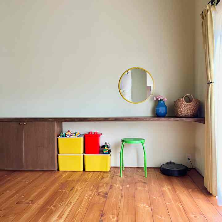 明るい黄色の収納ボックスと木目調の床、棚が配置されたシンプルなリビングスペース